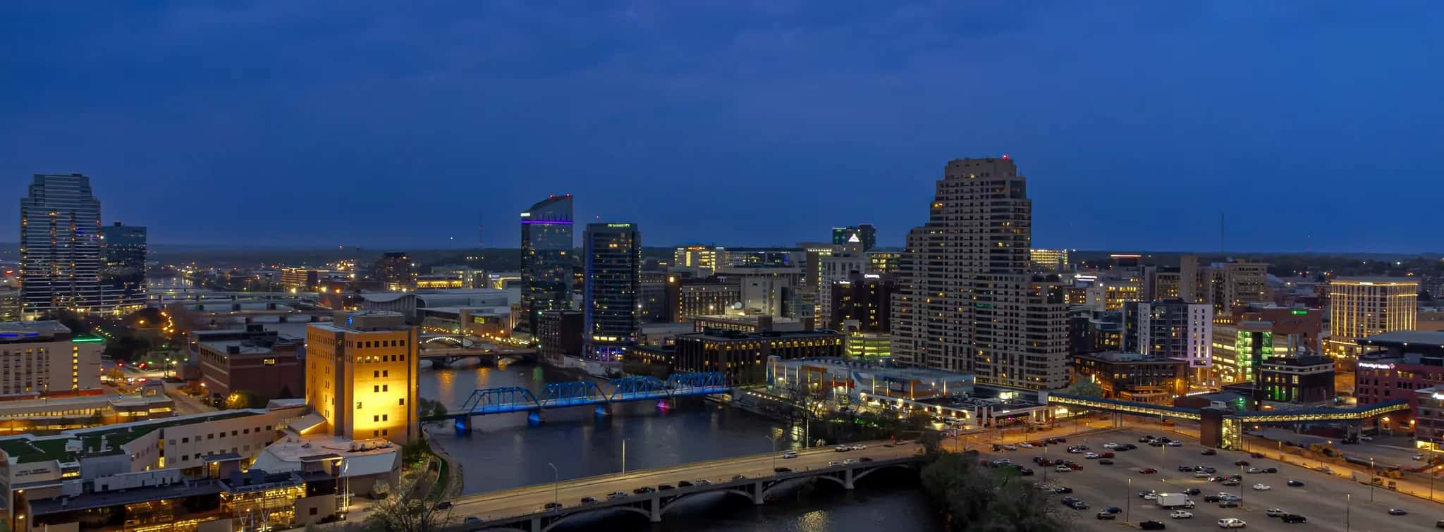 Downtown Grand Rapids, Michigan skyline along the Grand River at dusk, with the Blue Bridge lit up