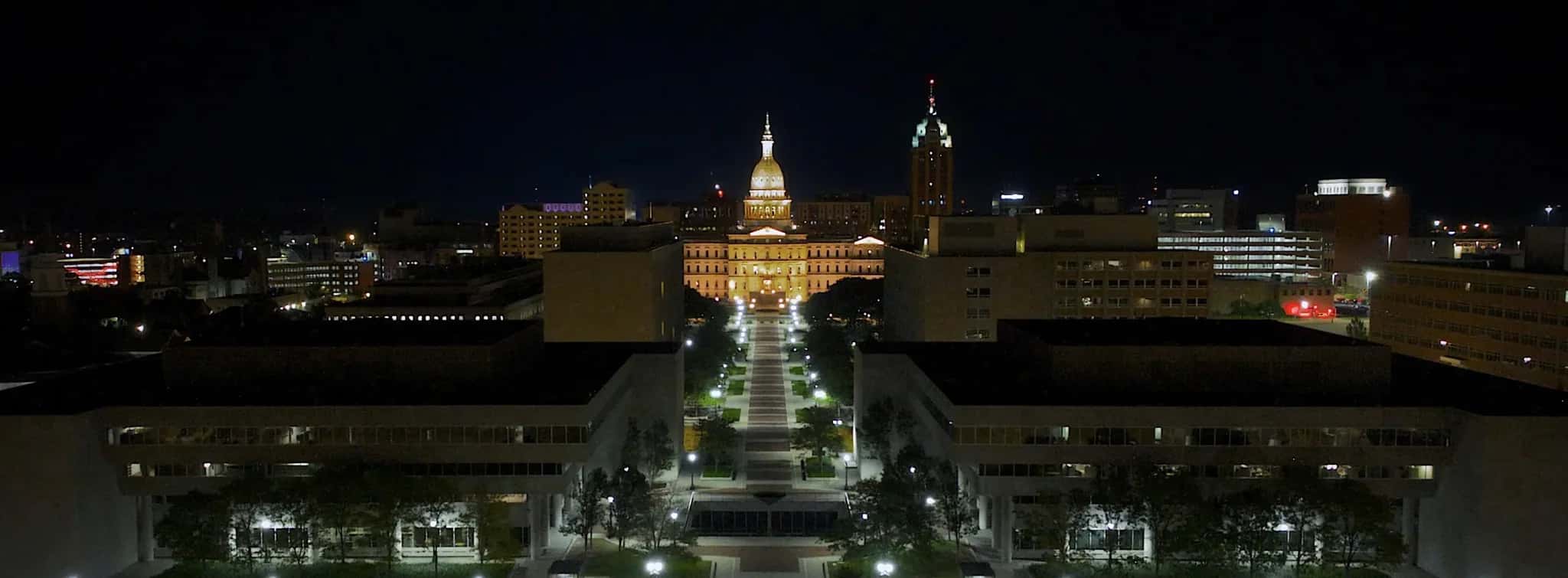 Michigan State Capitol lit at night at the end of the downtown Lansing skyline