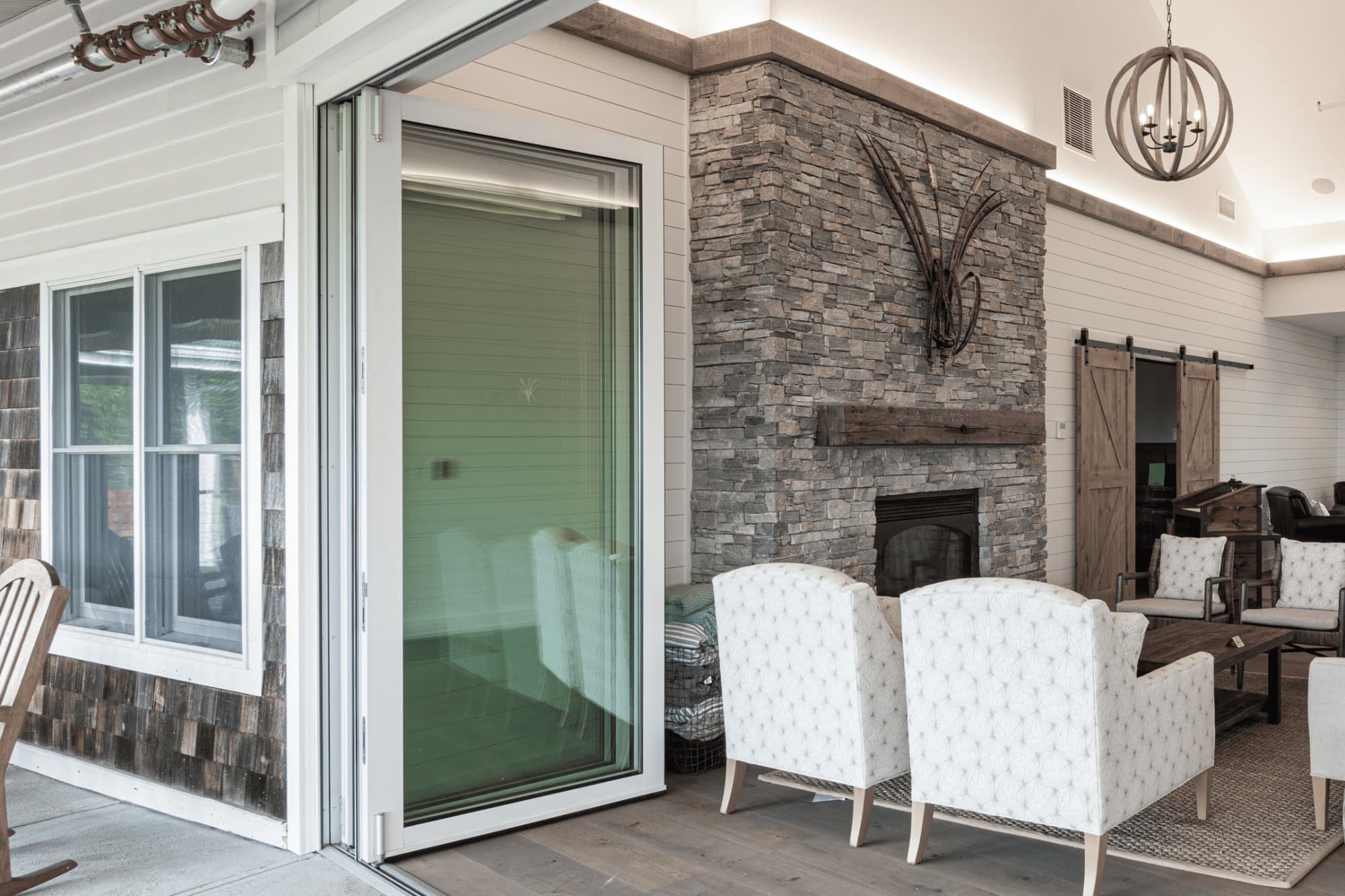 Euro-Wall Vista Fold folding glass panels stacked neatly at the end of an opening between a clubhouse lounge and its covered porch