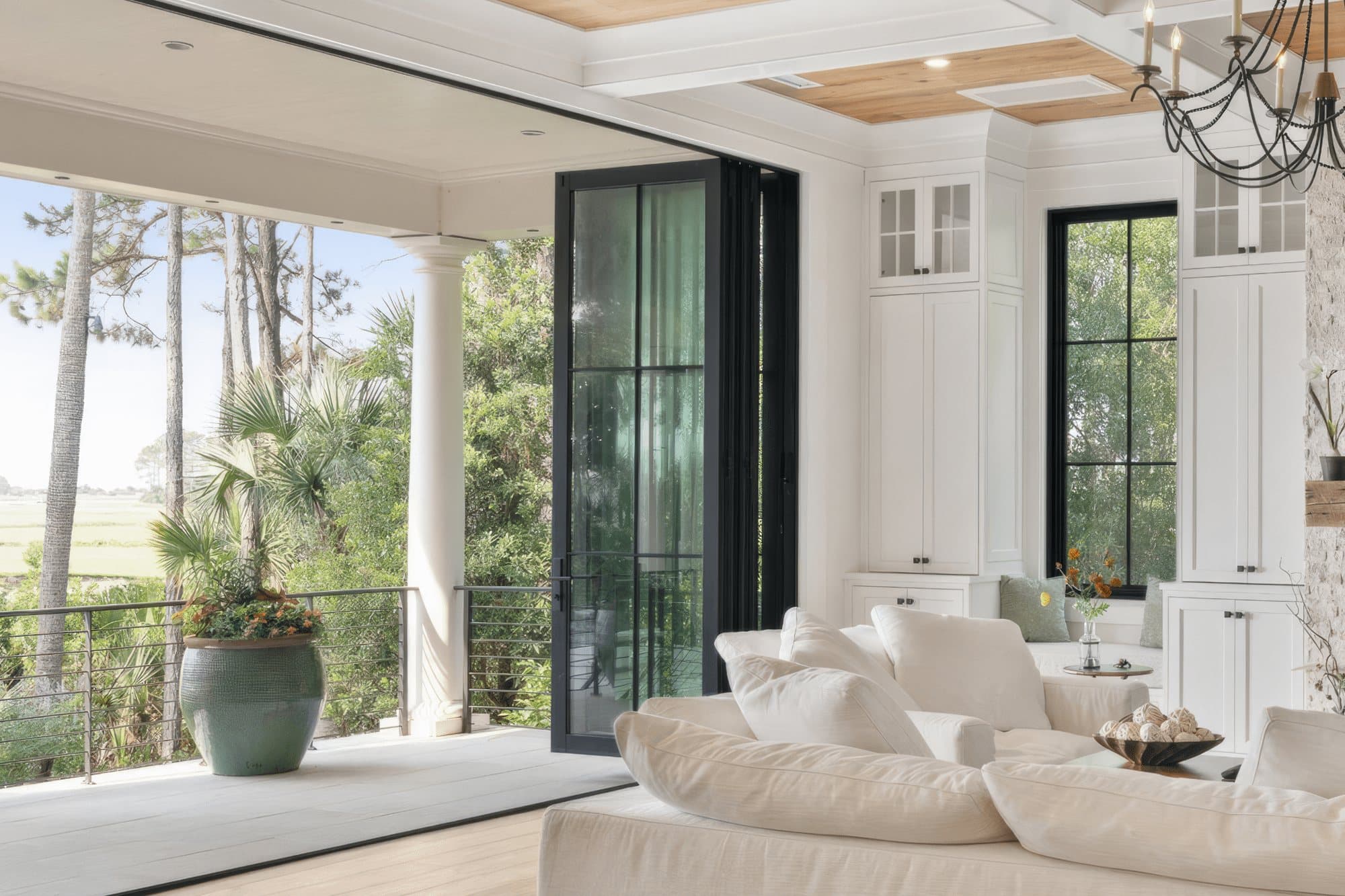 Euro-Wall Vista Fold folding glass doors with dark frames folded open from a living room to a columned porch