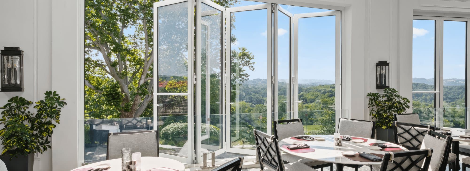 Wide view of a Euro-Wall Vista Fold thermally broken aluminum folding glass wall folded open across a dining room