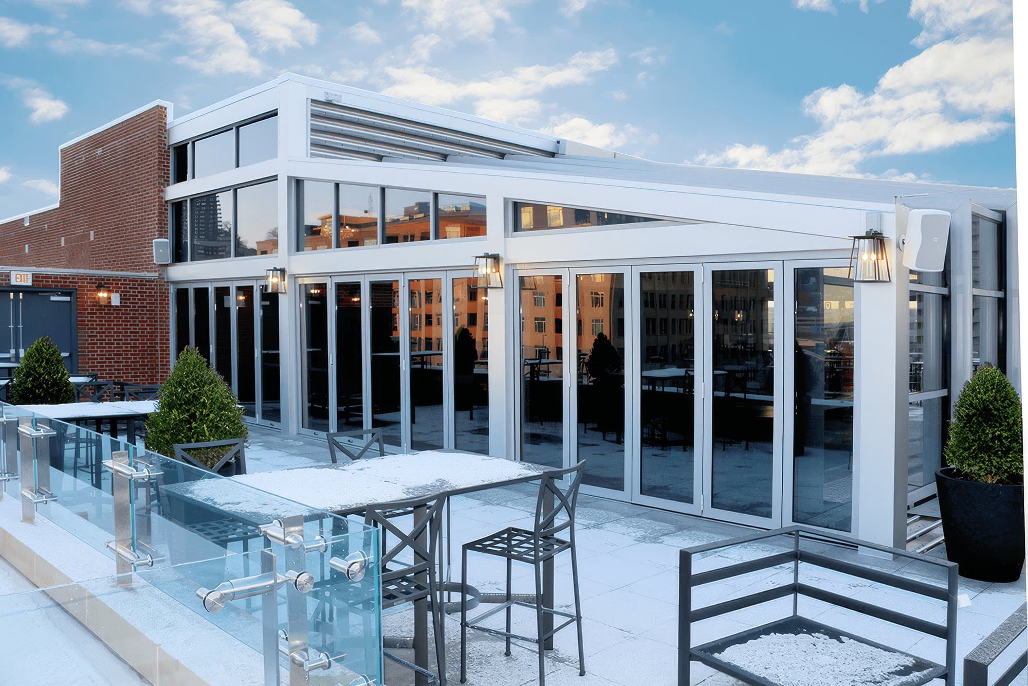 White-framed Euro-Wall Vista Fold folding glass wall along a hotel's elevated outdoor patio with glass railings