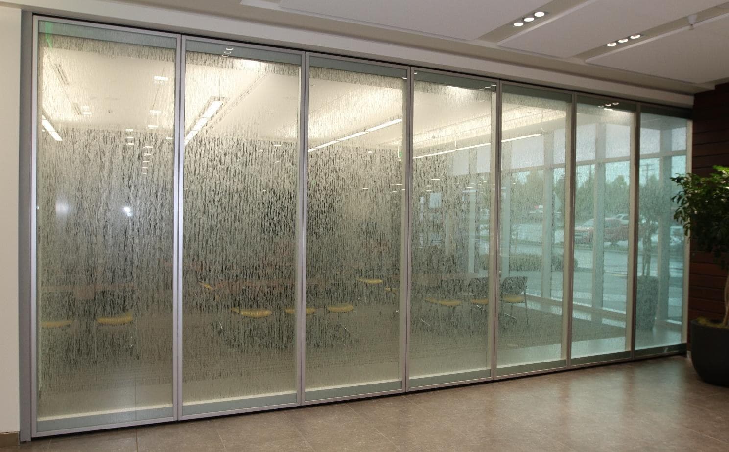 Full run of Modernfold Acousti-Clear glass operable wall panels with decorative textured glass in front of a meeting room