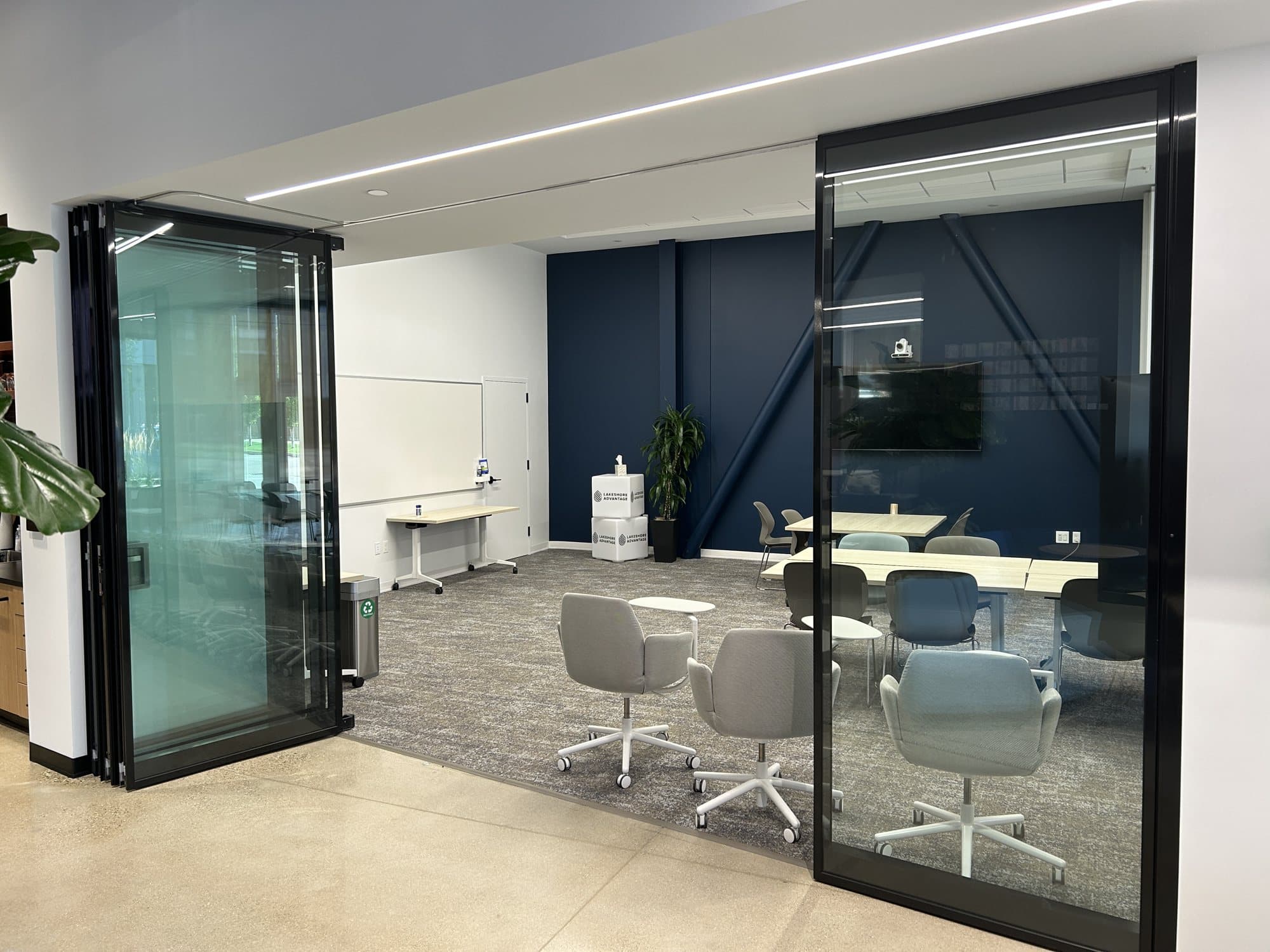 One black-framed Acousti-Clear single glass panel moved out of the stack across the Learning Lab opening at Lakeshore Advantage
