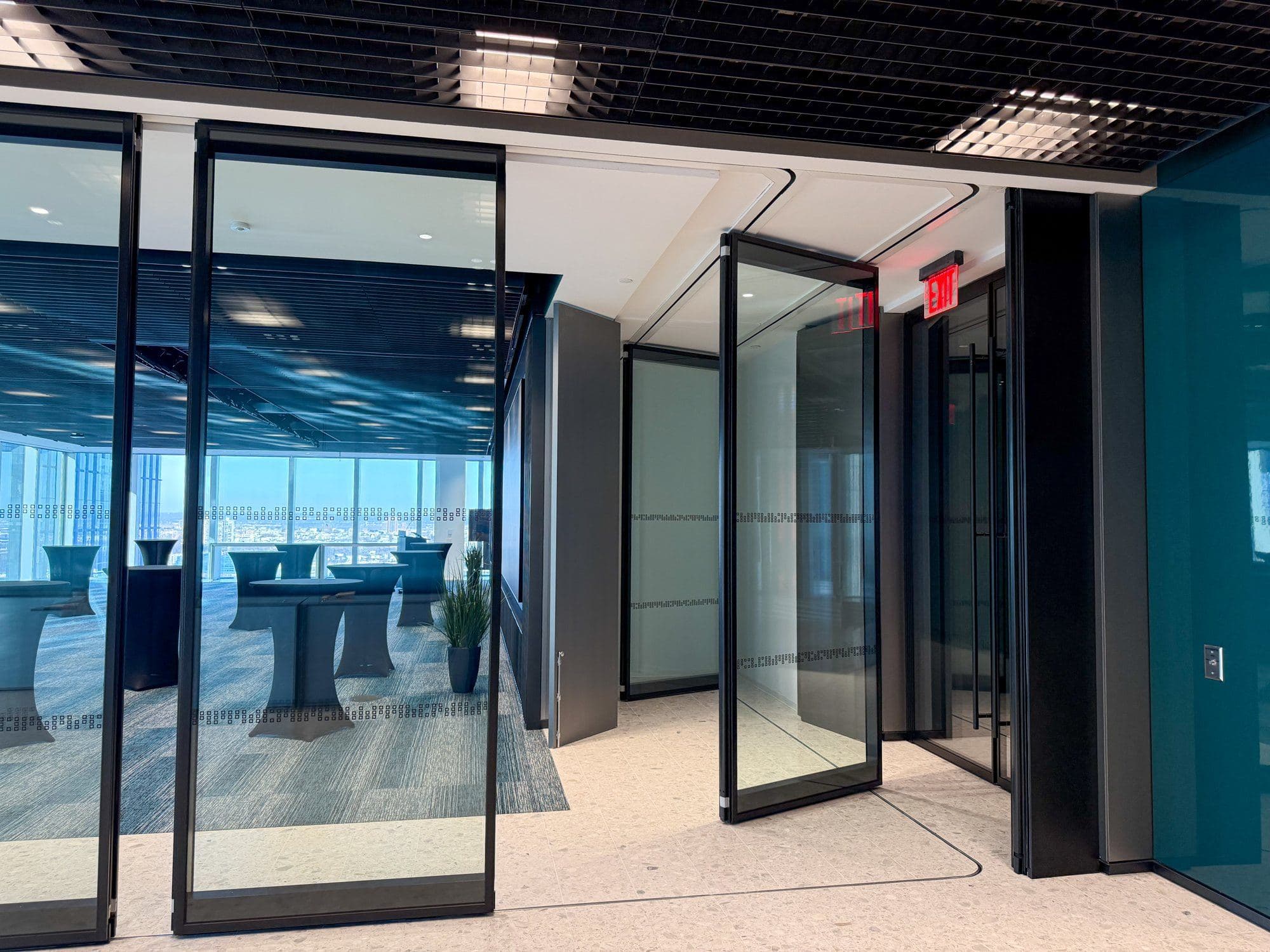Modernfold ComfortDrive glass panel pivoting into the stack pocket at AllianceBernstein, with the curved ComfortDrive track visible in the ceiling