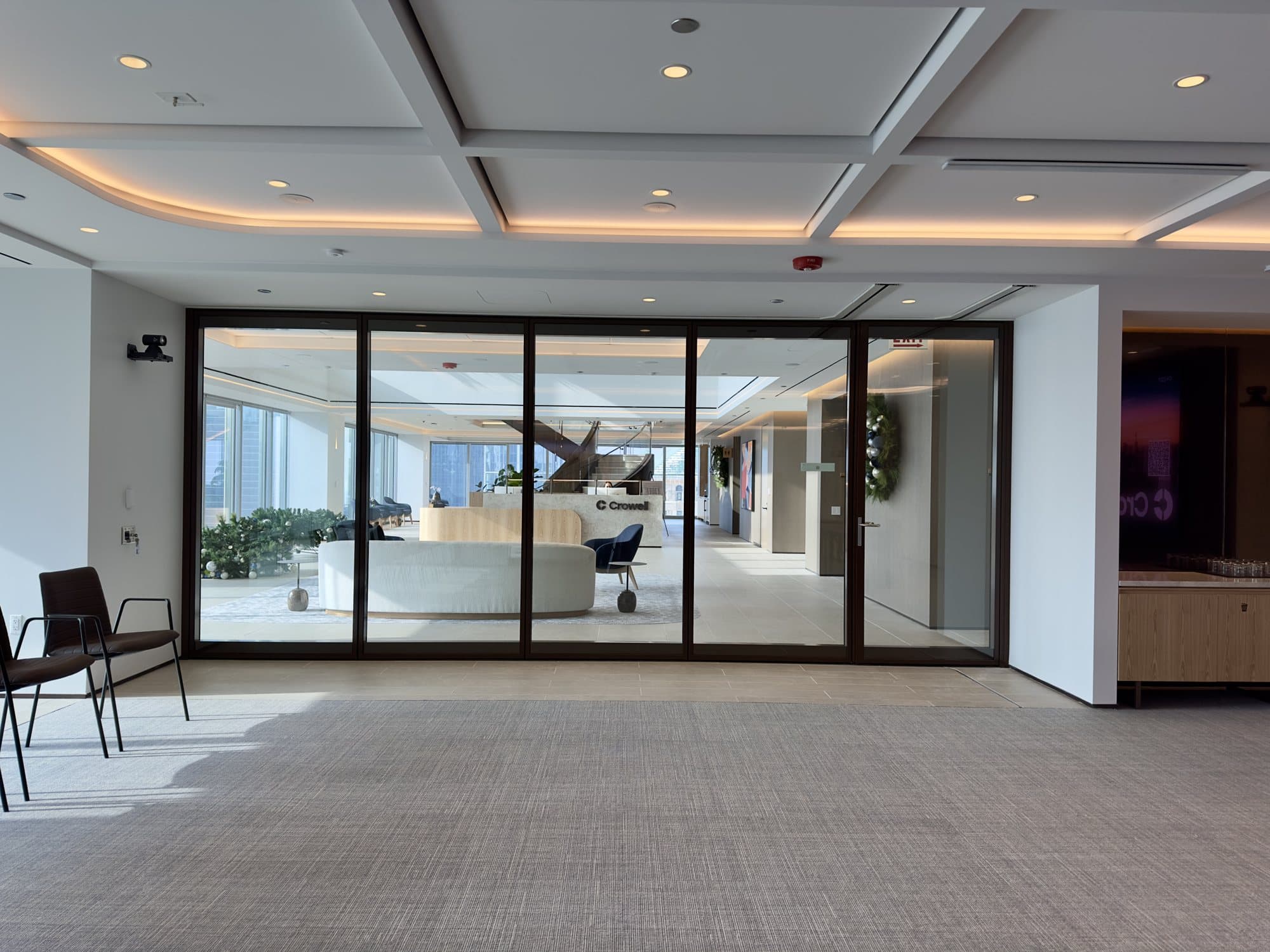 Fully closed bronze-framed Modernfold ComfortDrive glass operable wall at Crowell, seen from the conference side looking through the glass to the lobby