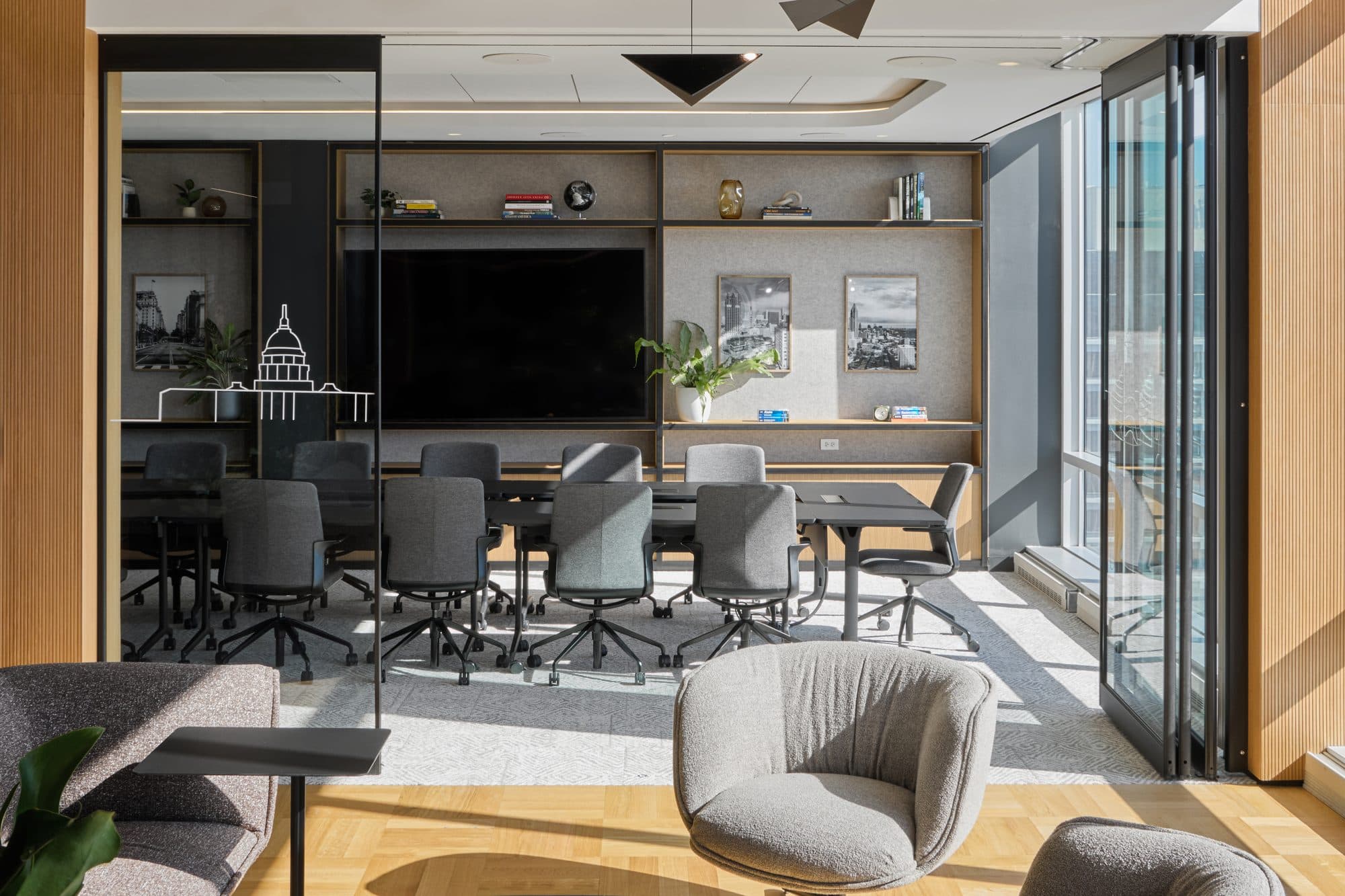 Modernfold PureView glass operable wall folded open at the side of a glass-walled boardroom, connecting it to an office lounge with daylight from the windows