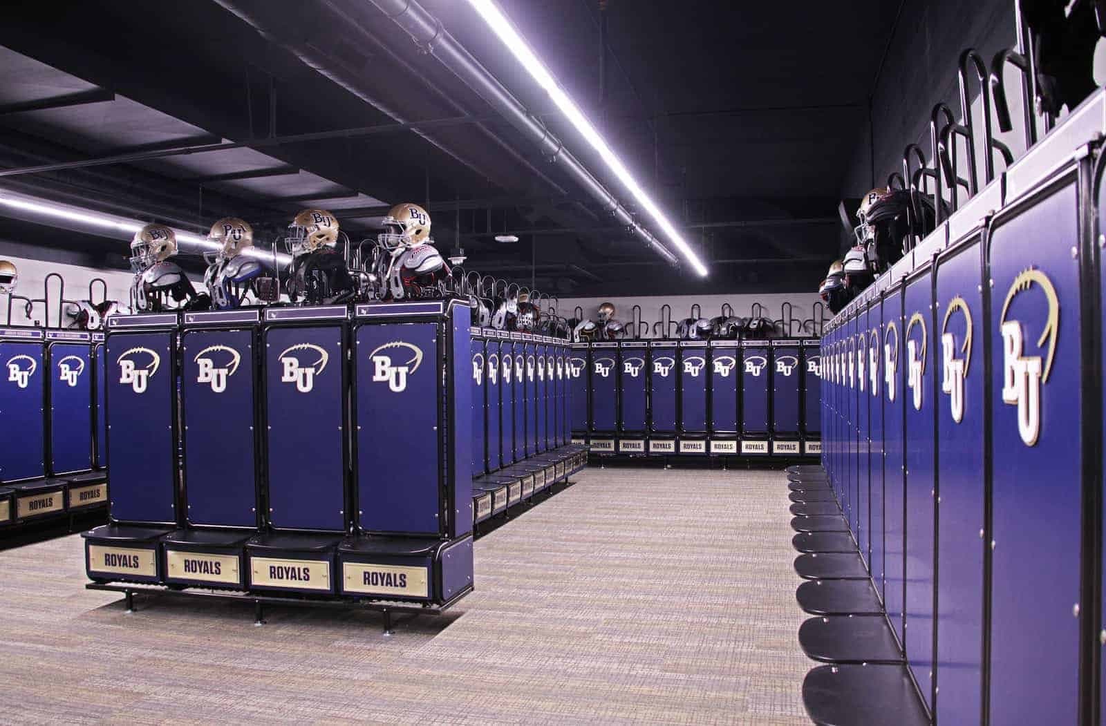 Football team locker room lined with GearGrid GridIron lockers, helmets and shoulder pads on top