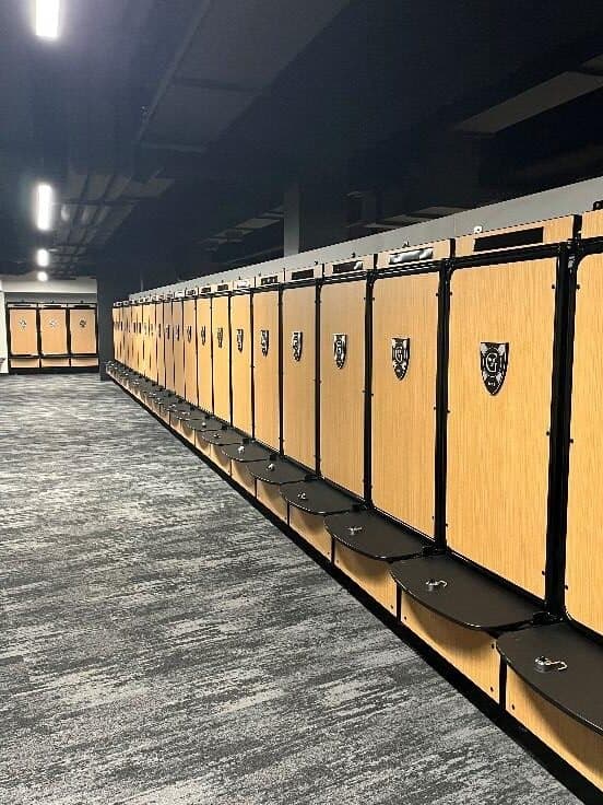 Long row of GearGrid GridIron team lockers with wood laminate doors and seats