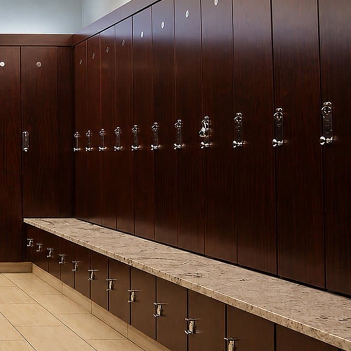 Dark woodgrain laminate lockers in a club locker room, with full-height doors above a stone-top bench and lower locker boxes