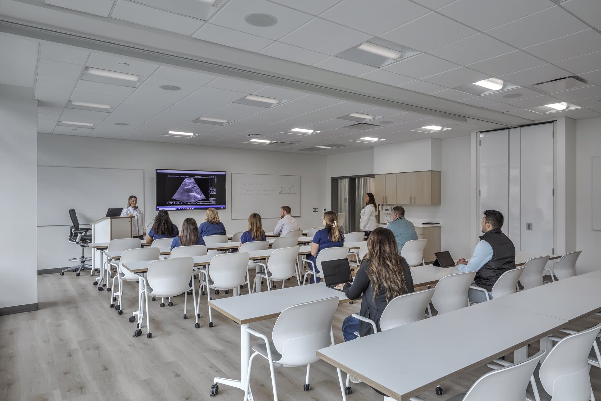 Modernfold folding panel partition stacked open at the right side of a Corewell Health nurse training classroom, leaving the full room clear for instruction