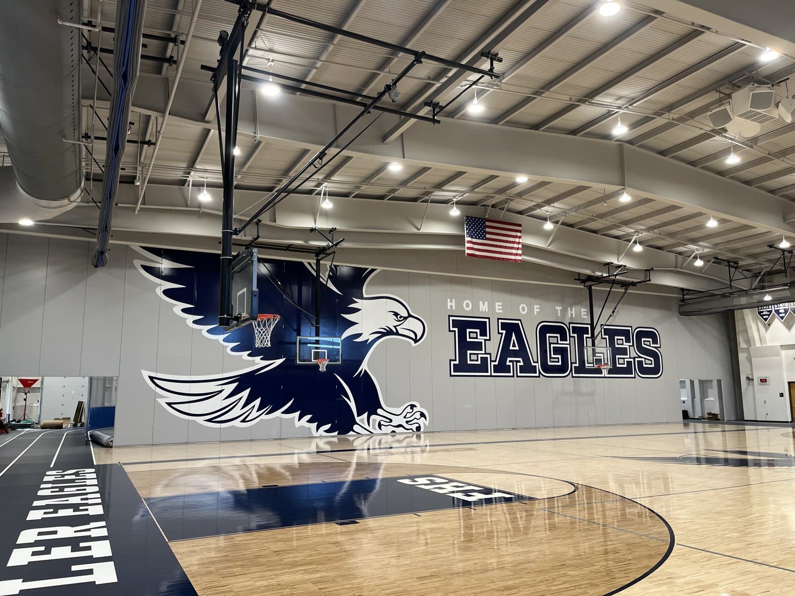Large Modernfold gym divider wall with a custom Eagles mascot graphic and “Home of the Eagles” lettering at Fowler High School
