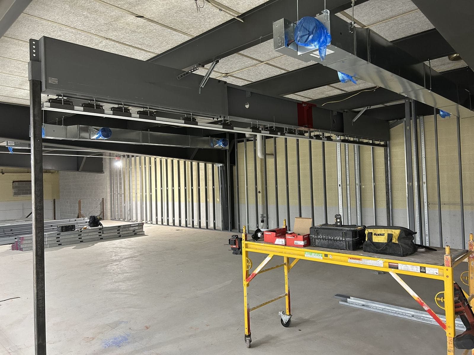 Operable wall track suspended below a gray steel box truss, with the end post in the foreground and ductwork above