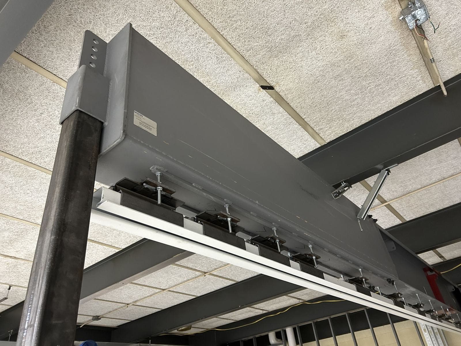 Close-up of the steel truss end on its post, with hanger rods and brackets holding the operable wall track below