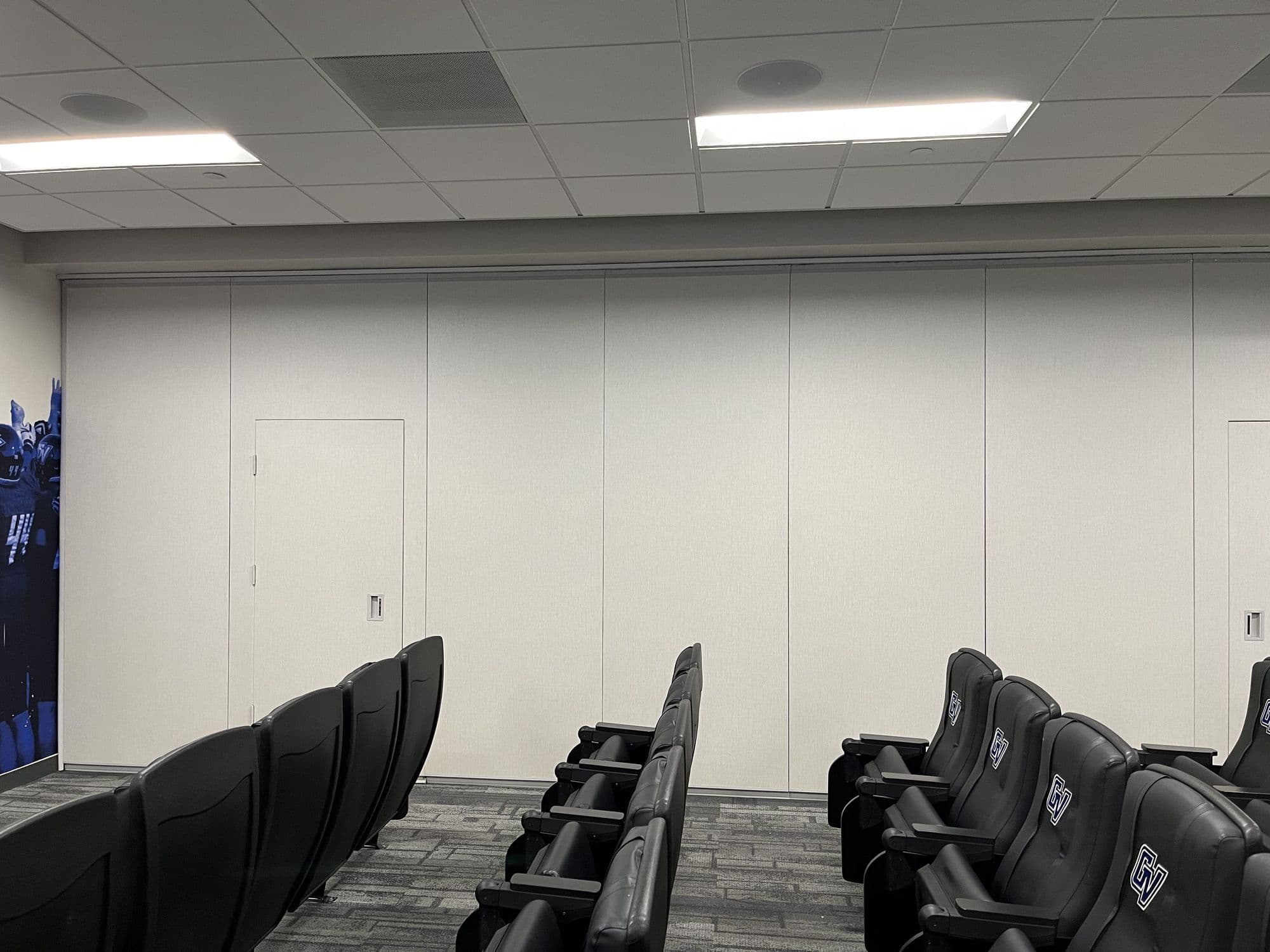 Straight-on view of the closed Acousti-Seal folding panel partition with a pass door dividing the GVSU football film room