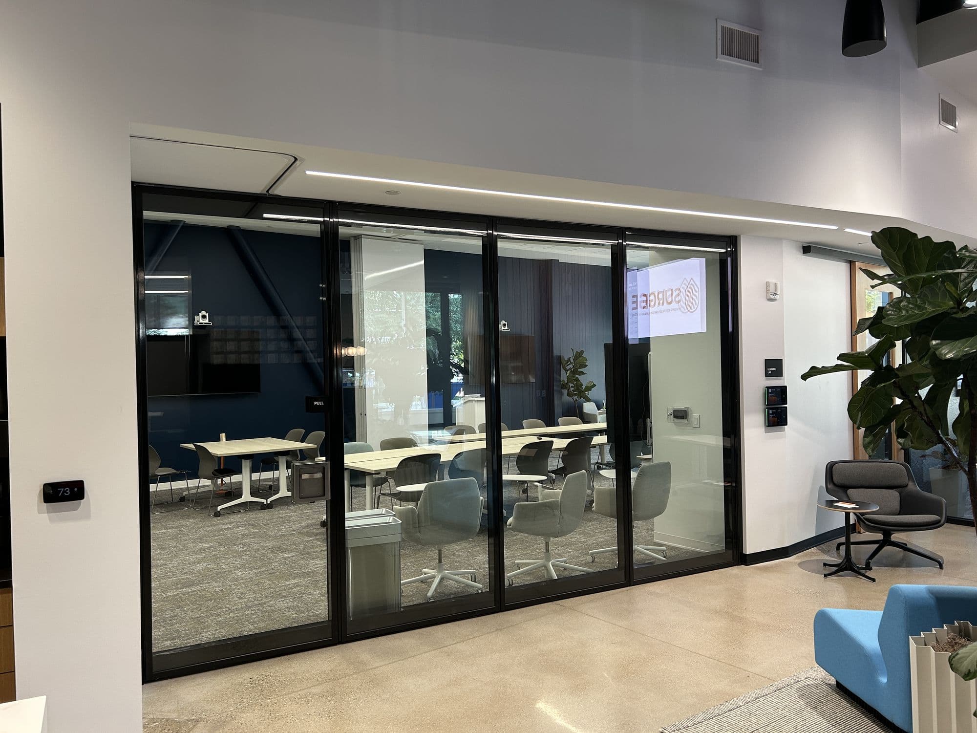 Closed glass operable wall at Lakeshore Advantage seen from the lobby with a blue chair in front