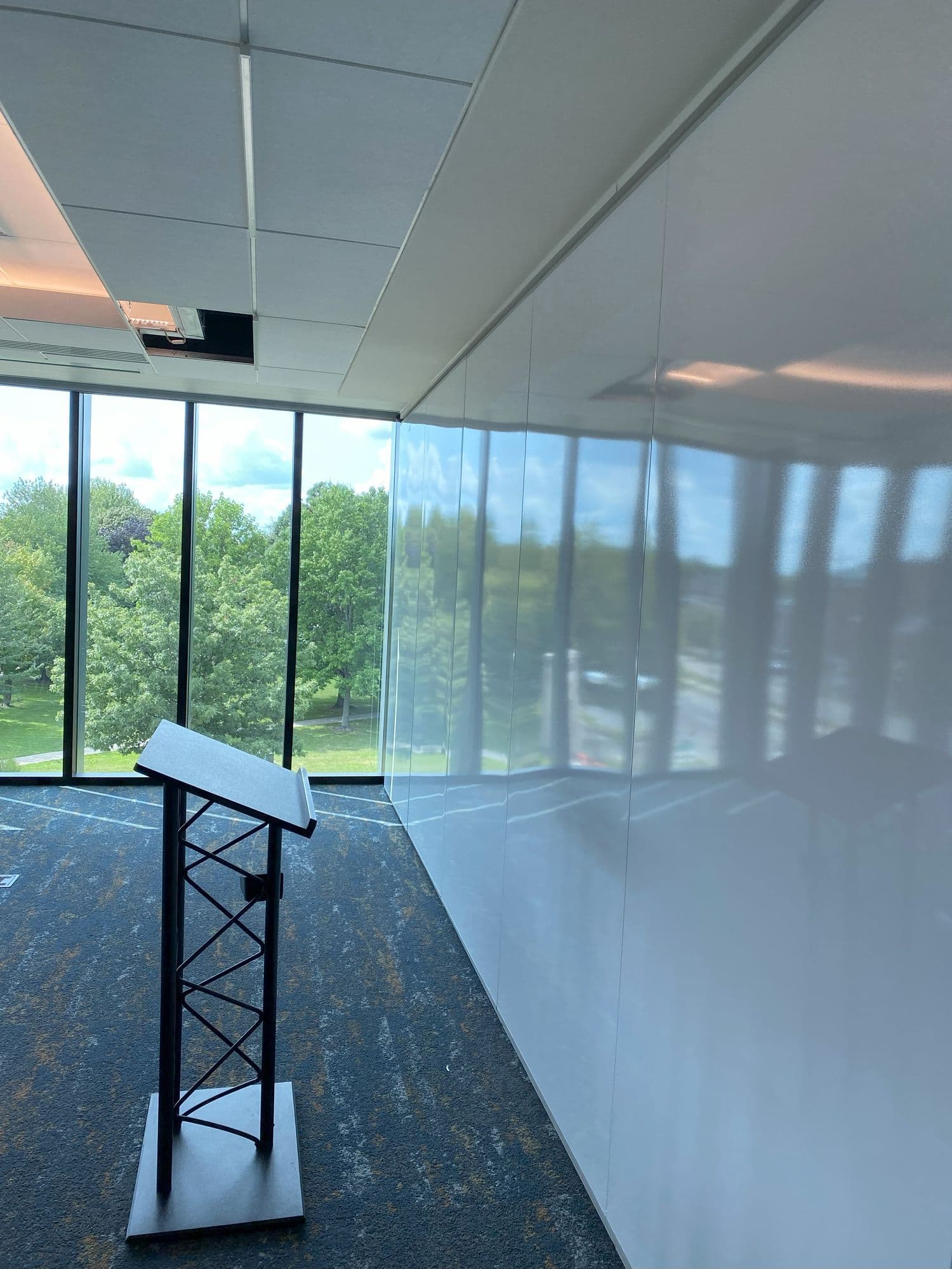 Closed markerboard partition meeting the window wall beside a podium at Michigan Realtors