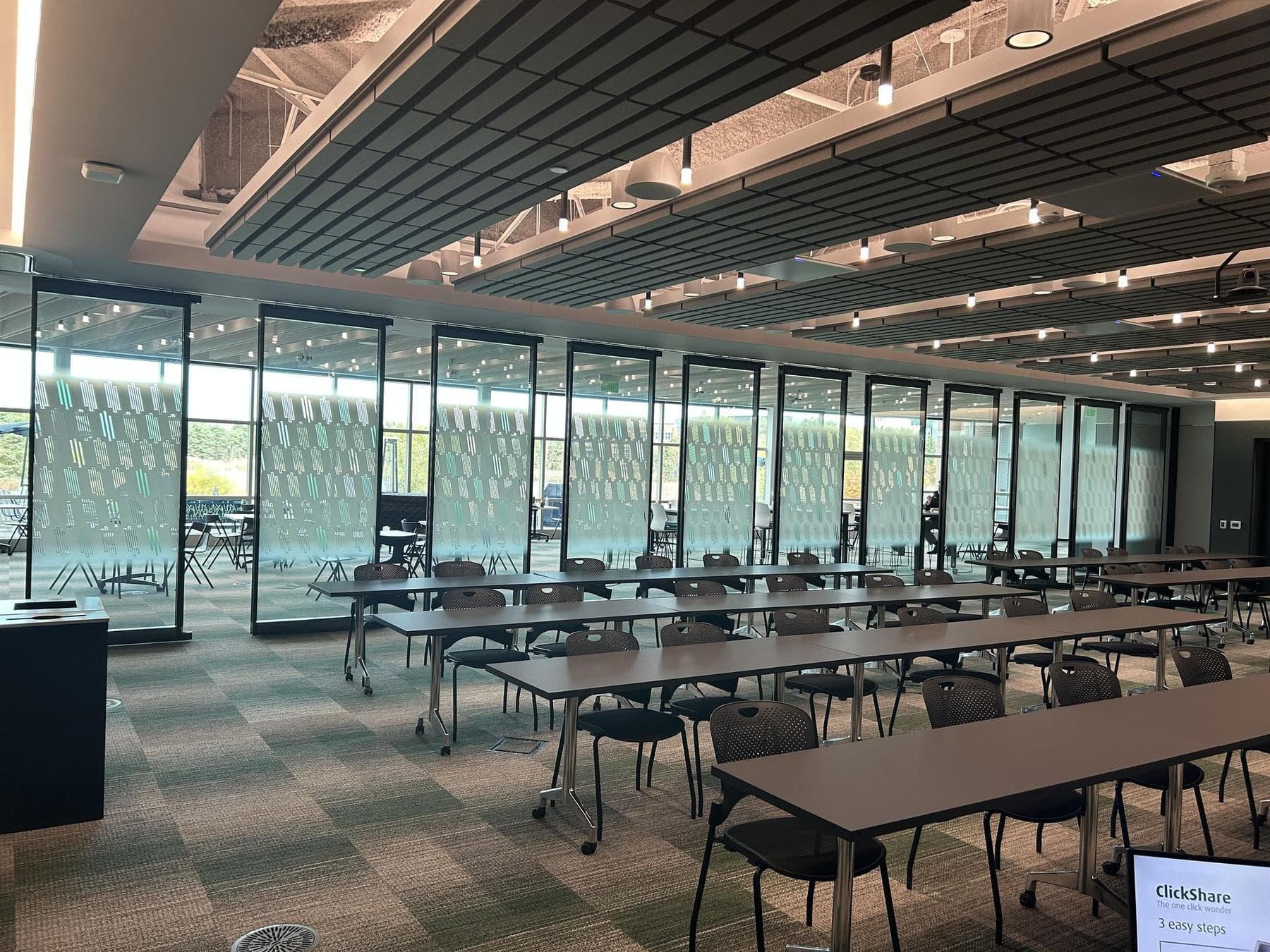 Acousti-Clear glass partition with Creative Film glass behind rows of training tables and chairs