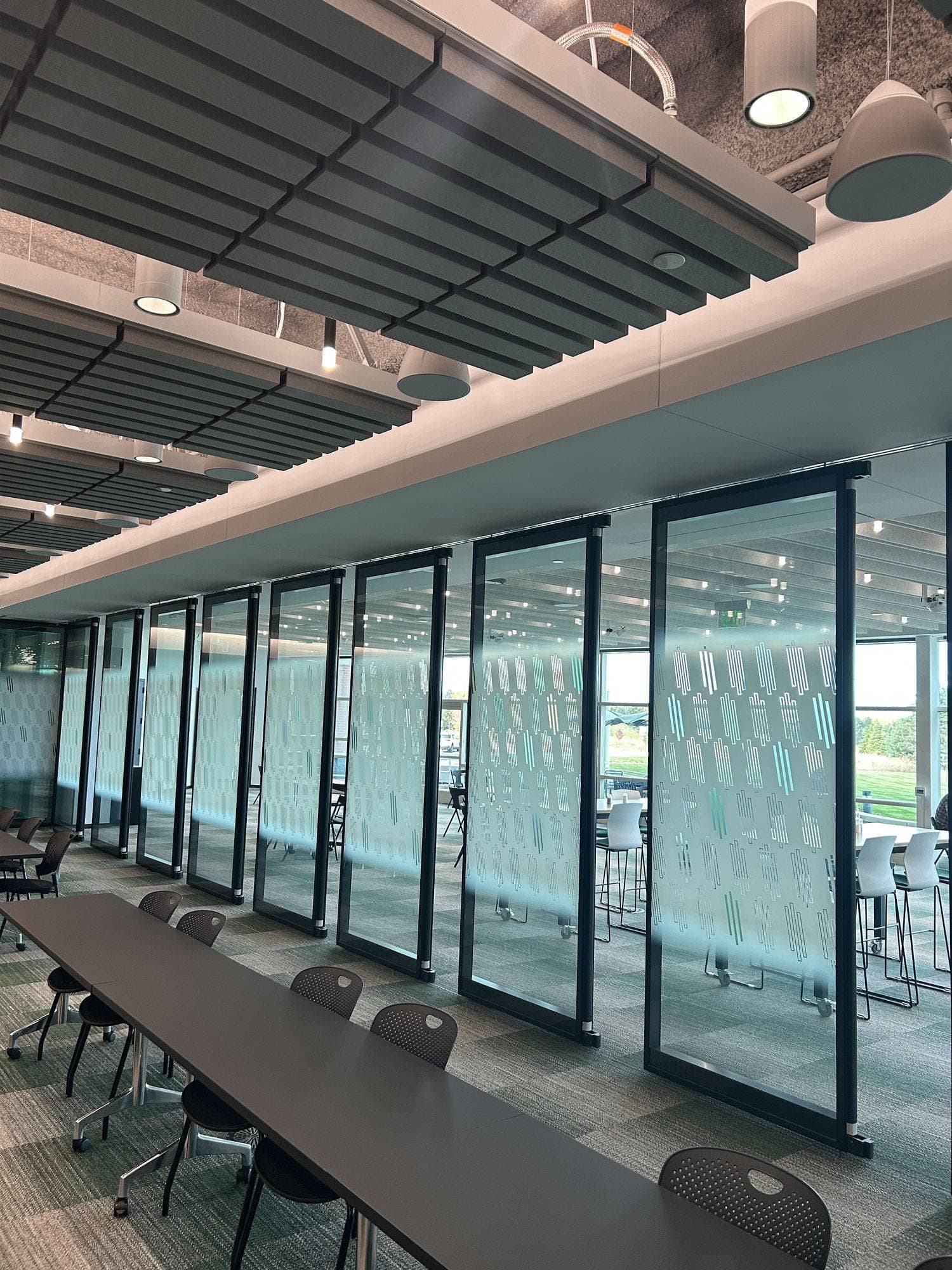 Row of Acousti-Clear glass panels with Creative Film alongside a long training table