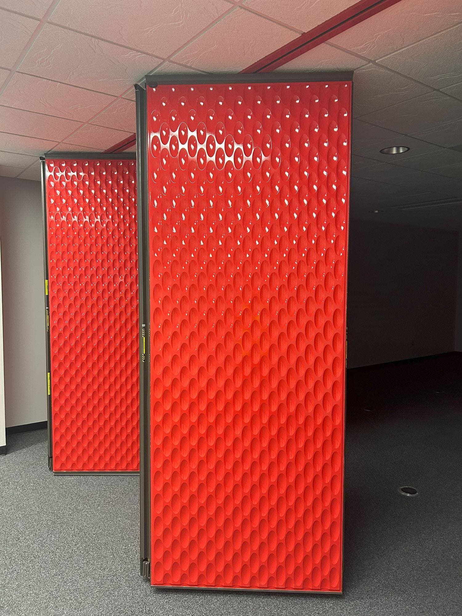 A folded pair of red designer line Acousti-Seal panels hanging from the ceiling track at Switch