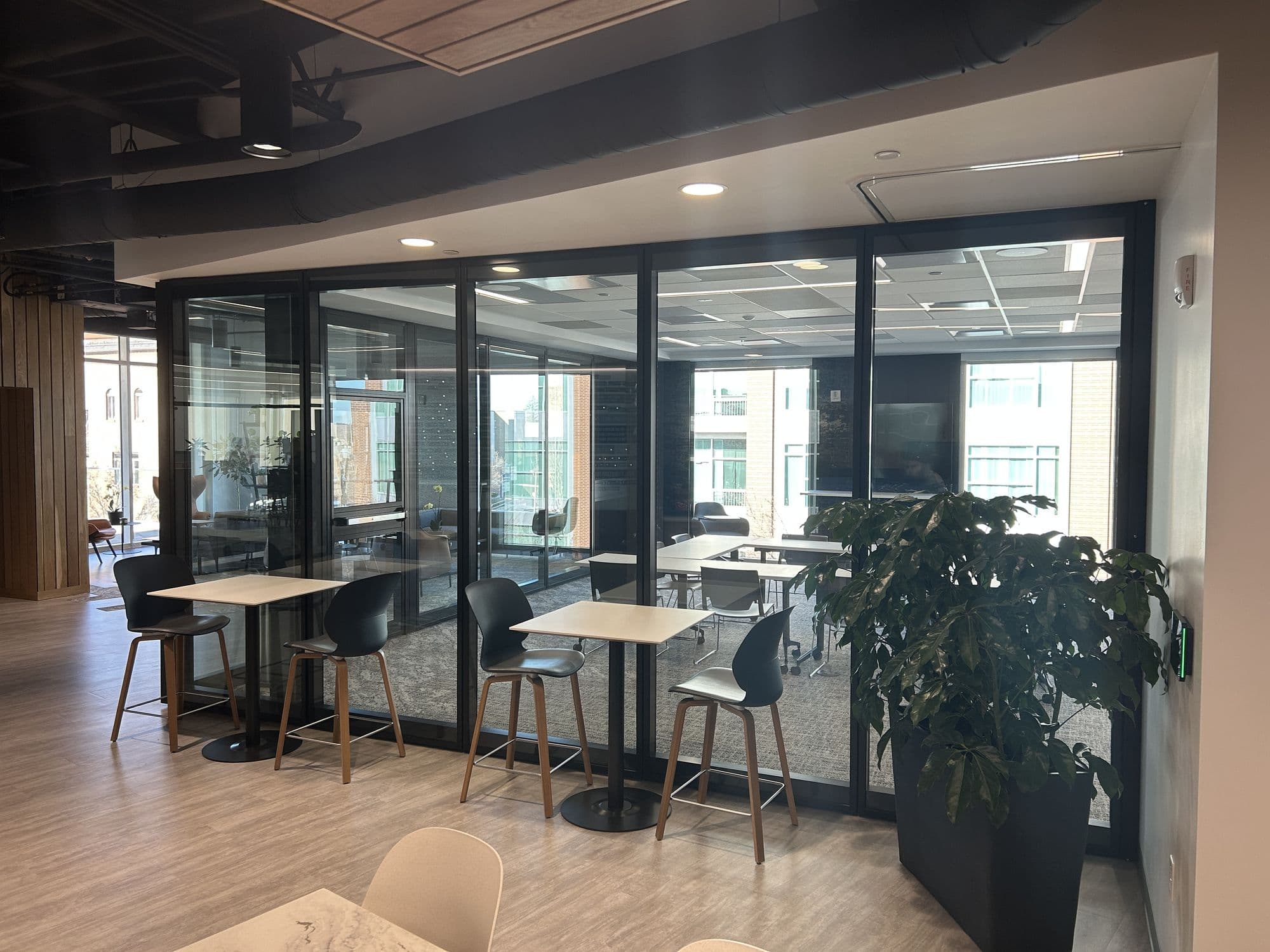 Closed glass operable wall with high-top tables and a plant at the West Coast Chamber of Commerce