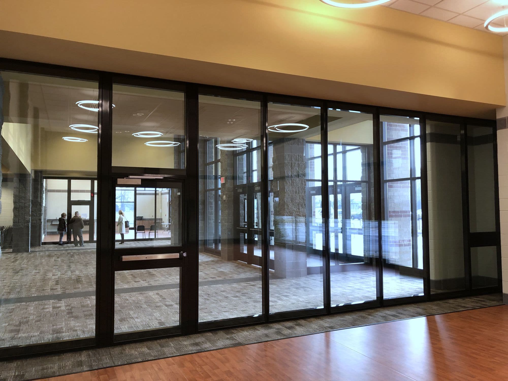 Closed Acousti-Clear glass wall at Zeeland East High School seen at an angle from the side with the red tile floor
