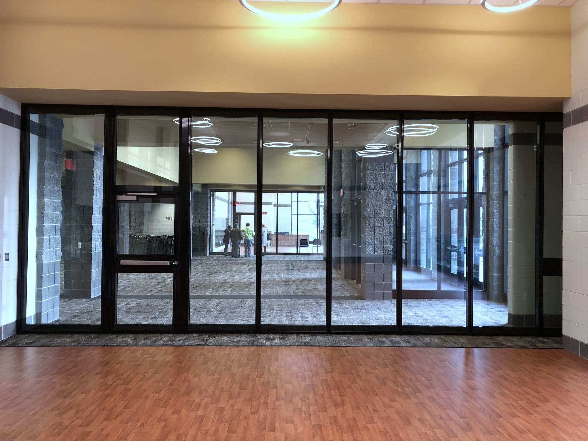 Closed Acousti-Clear glass wall at Zeeland East High School seen straight on from the side with the red tile floor