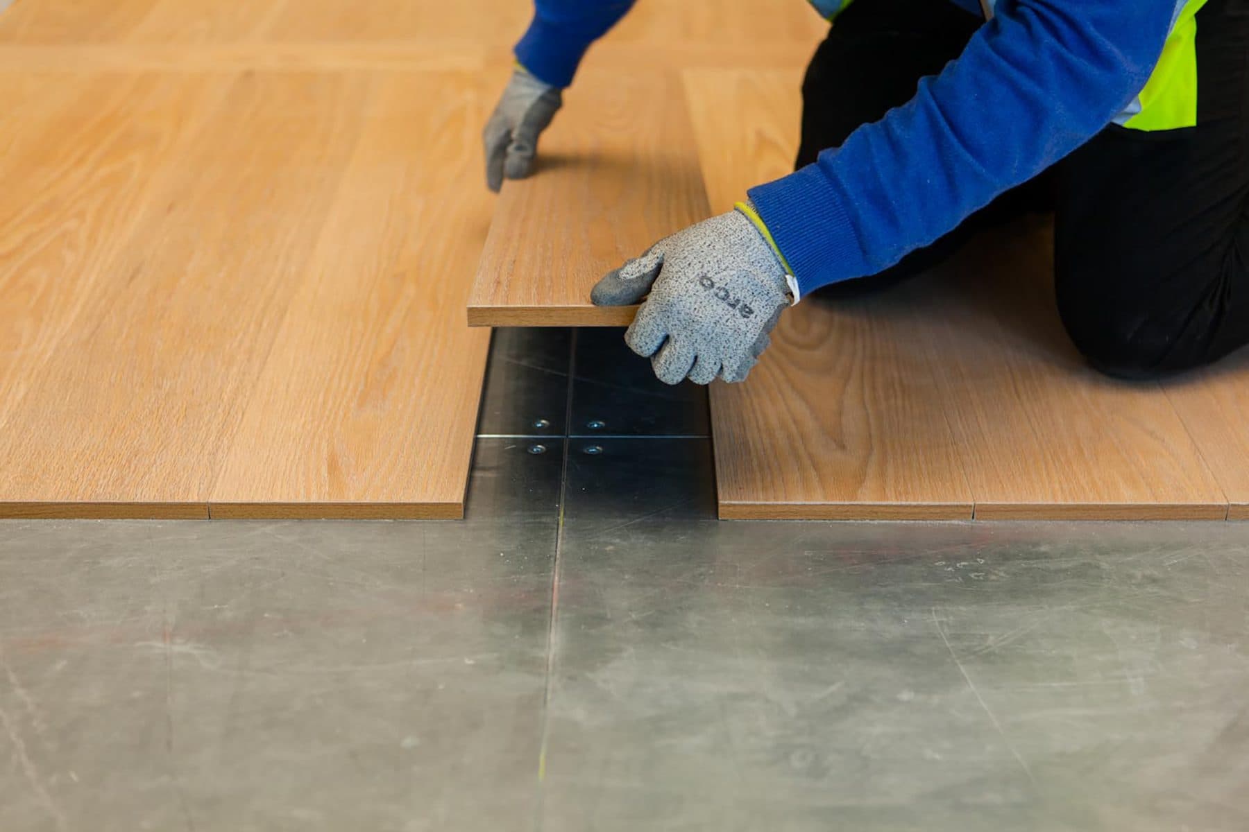 Installer laying magnetic freelay wood planks over steel access floor panels