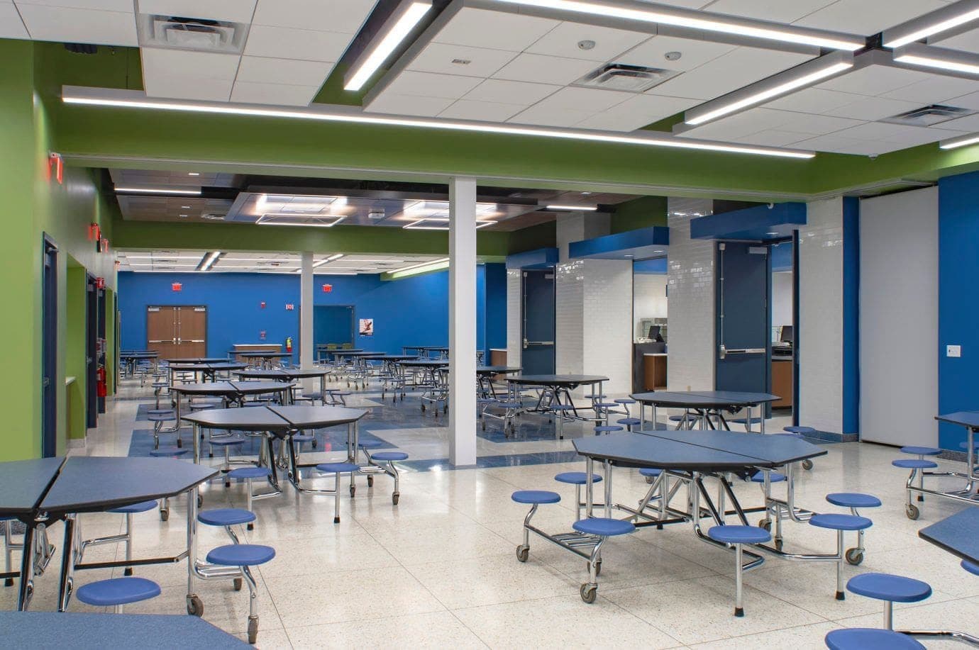School cafeteria with round tables on a light terrazzo-finish raised access floor