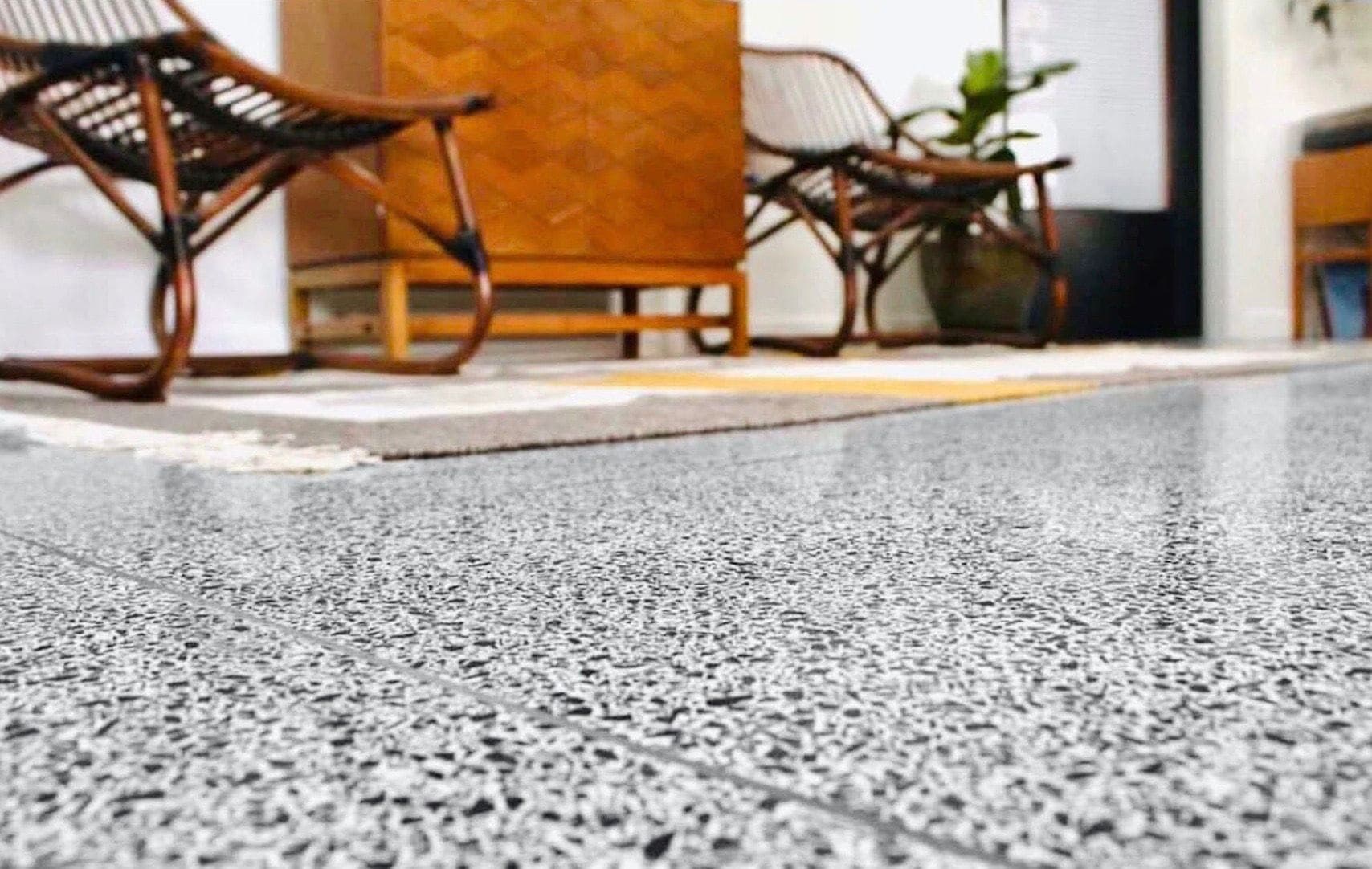 Close-up of a speckled terrazzo finish on a raised access floor beside lounge chairs