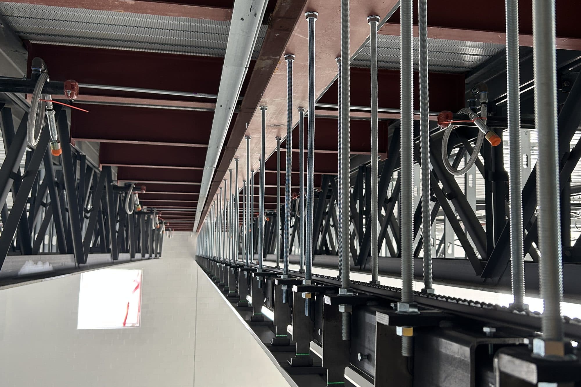 Operable wall track hung on threaded rods from overhead steel beams, with the support steel running the length of the opening