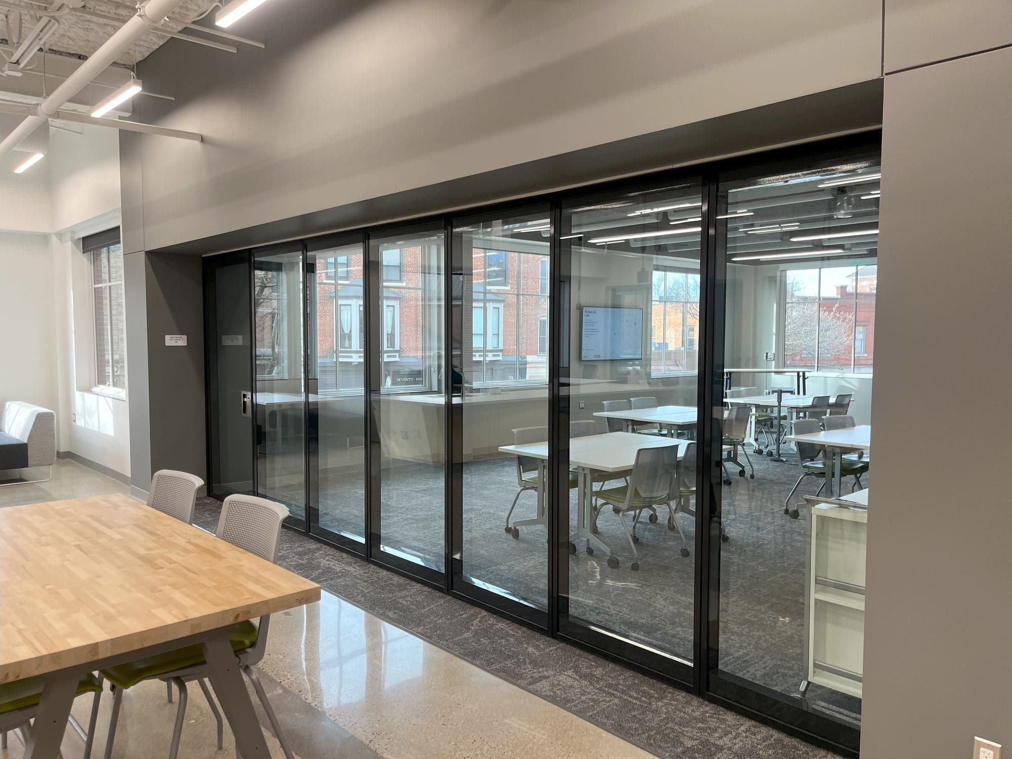 Closed Modernfold Acousti-Clear paired panel glass wall with black frames dividing the open office from a training room at GMB Architecture HQ in Holland