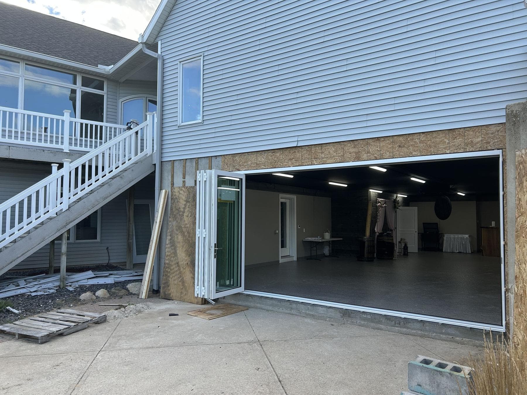 Euro-Wall folding glass door fully open at the walkout lower level of the Hancock Residence, with the panels stacked to one side and the deck stairs beside it