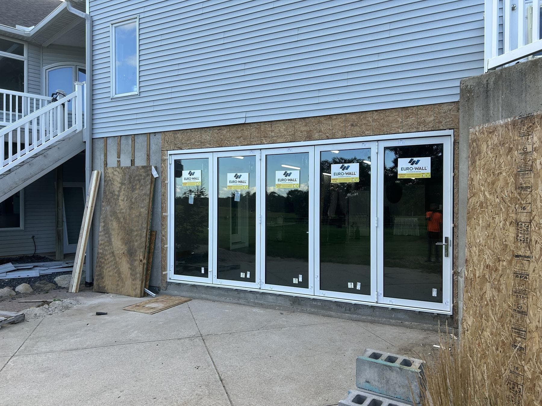 Closed Euro-Wall folding glass door with five white-frame glass panels across the lower level of the Hancock Residence, seen at an angle