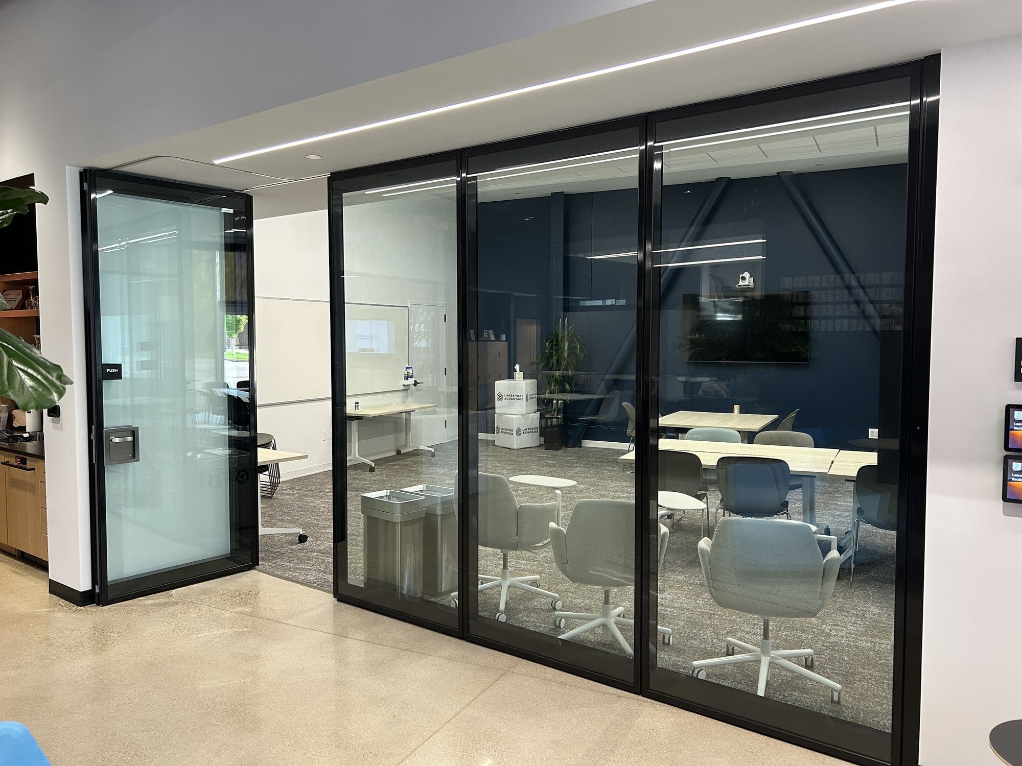 Closed Modernfold Acousti-Clear glass wall with black frames enclosing a conference room at Lakeshore Advantage