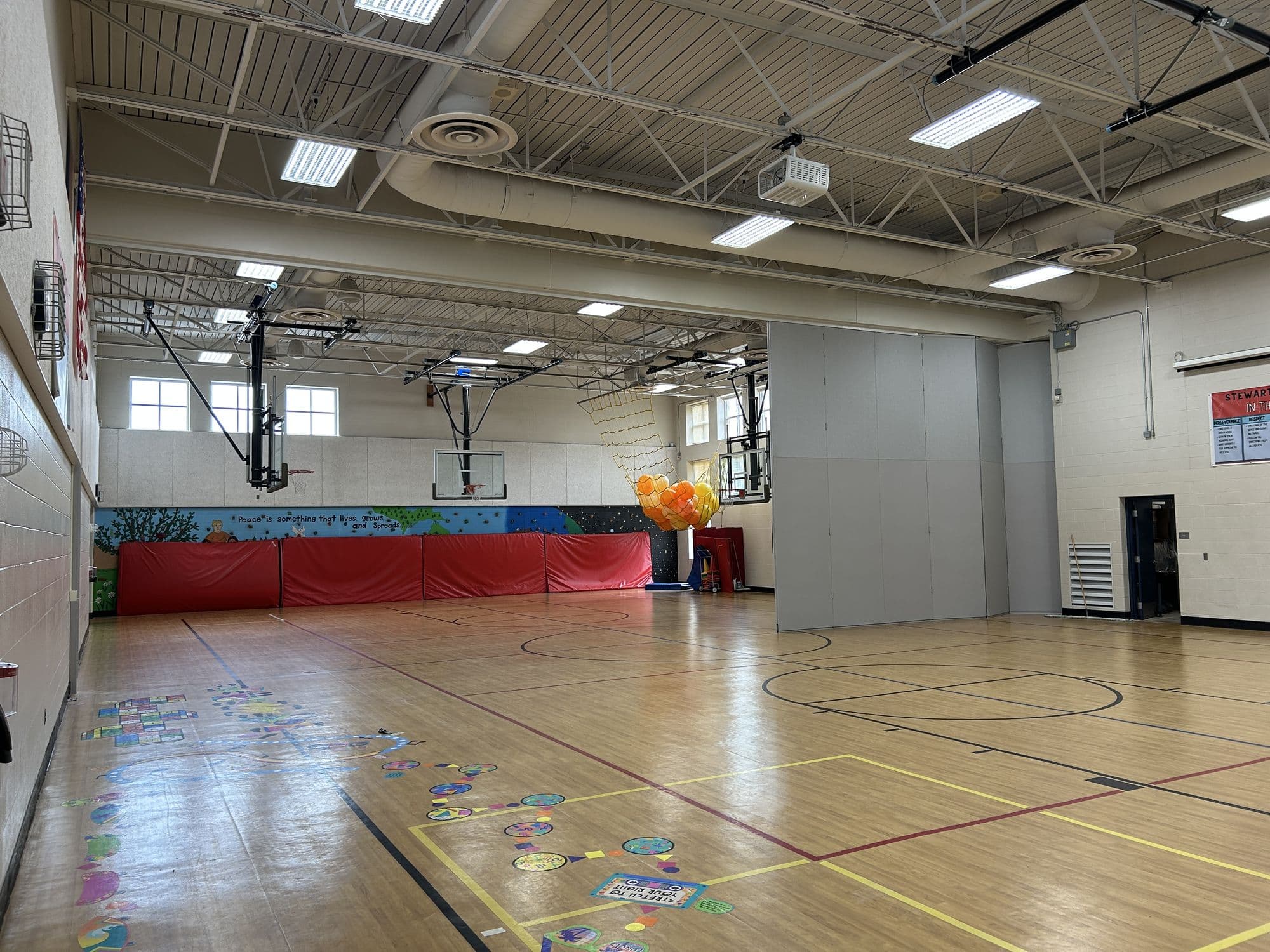 Modernfold Acousti-Seal Premier Electric wall partly extended across the Stewart Elementary gym, its two-tone gray panels traveling out from the stack
