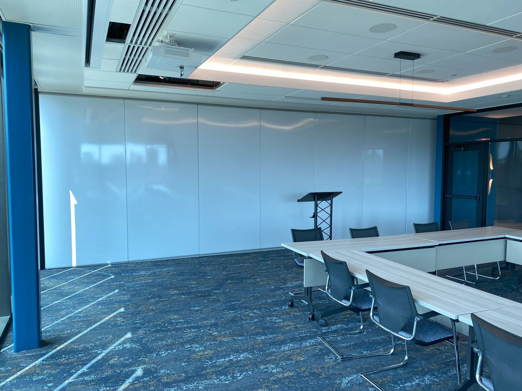 Closed markerboard-finish folding panel partition behind a podium in the Michigan Realtors boardroom