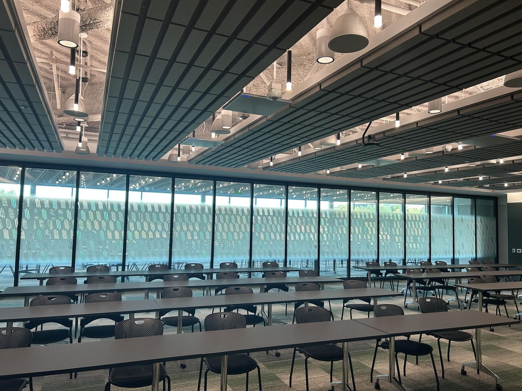 Wide view of a large training room with rows of tables and a long Acousti-Clear glass wall across the far side